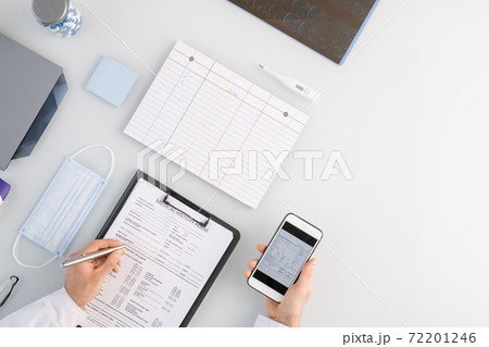Overview of medical worker hands over history form while scrolling through data 72201246