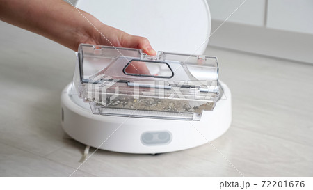 Woman opens robot vacuum cleaner show container with rubbish Woman opens robot vacuum cleaner show container with rubbish 72201676