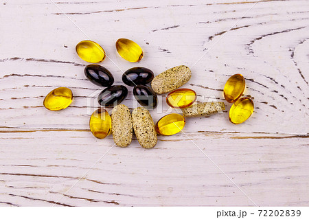 Mixed natural food supplement pills, omega 3, multivitamin capsules on a white wooden table Mixed natural food supplement pills, omega 3, multivitamin capsules on a white wooden table 72202839