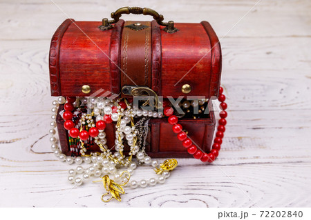 Vintage treasure chest full of jewelry and accessories on white wooden background Vintage treasure chest full of jewelry and accessories on white wooden background 72202840
