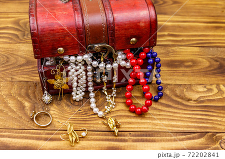 Vintage treasure chest full of jewelry and accessories on wooden background Vintage treasure chest full of jewelry and accessories on wooden background 72202841