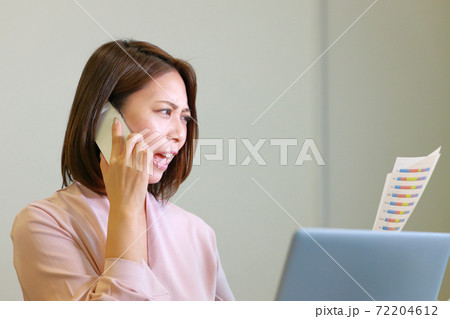資料を持ち電話で怒っている女性 資料を持ち電話で怒っている女性 72204612