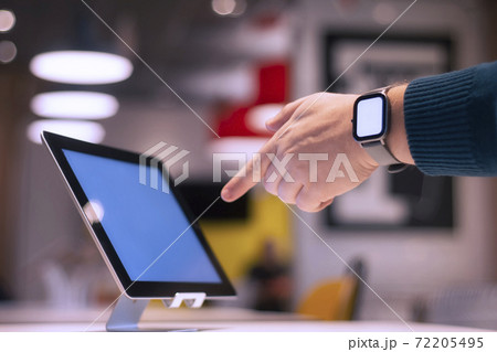 Mock-up of a smart watch with a white screen on a man's hand. Businessman shows a finger into the screen of the tablet on the background of the cafe. 72205495