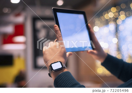 Businessman with smart watch and digital tablet with a white screen in his hands. A male freelancer works in a cafe. Businessman with smart watch and digital tablet with a white screen in his hands. A male freelancer works in a cafe. 72205496