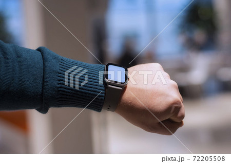 A man with a smartwatch and a white screen mockup on his hand. A man uses a fitness tracker on the background of a shopping mall. 72205508