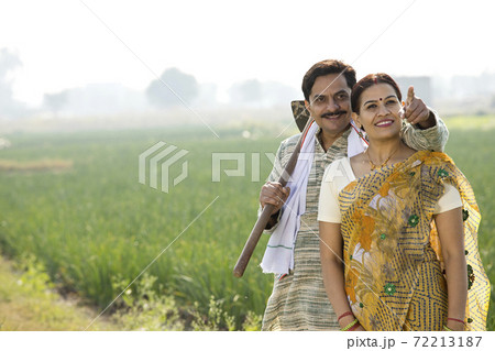 Happy Indian couple farmers examining crop in agricultural field 72213187