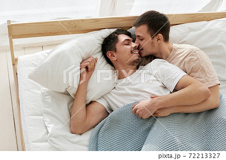 Happy Gay Couple Lying On Bed At Homeの写真素材