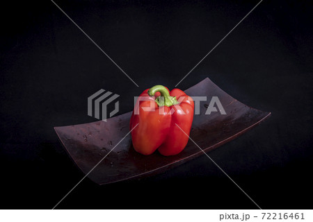 Old wooden Japanese tray with red pepper on black background Old wooden Japanese tray with red pepper on black background 72216461
