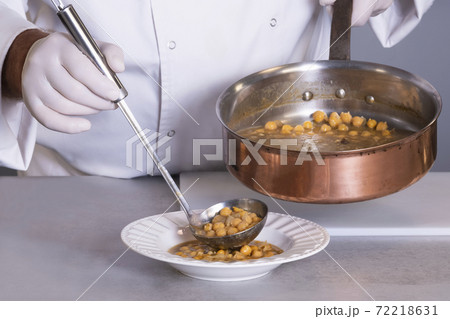view of chickpea stew being served by a male chef using a ladle on an out of focus background view of chickpea stew being served by a male chef using a ladle on an out of focus background 72218631