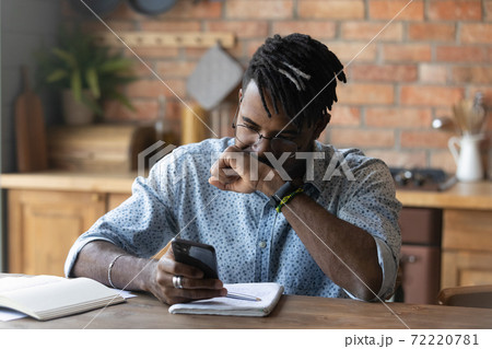 Stressed young biracial guy in glasses reading message with bad news. Stressed young biracial guy in glasses reading message with bad news. 72220781