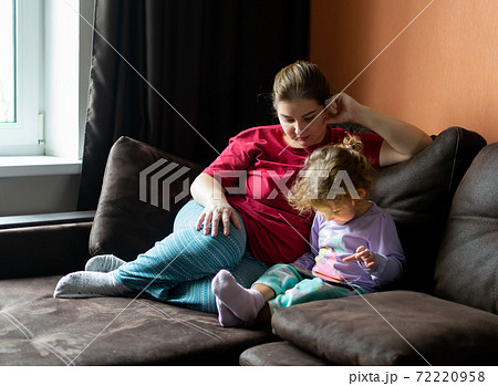 Mother and daughter at home use tablet pc. Motherhood, spending time with a child. Parental love. 72220958