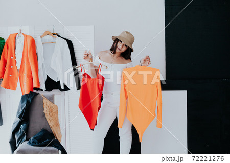 Portrait of happy young smiley brunette woman choosing outfit from wardrobe closet with stylish clothes Portrait of happy young smiley brunette woman choosing outfit from wardrobe closet with stylish clothes 72221276