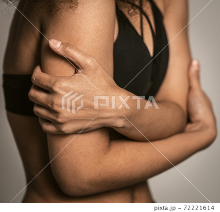 Close up. Timidity, panic attack, self-preservation, fear African American girl standing covered with hands in black bare shoulder top isolated on grey background. Human emotions 72221614