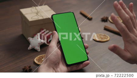 man hand chat with smartphone with green screen with christmas gifts and decorations on background man hand chat with smartphone with green screen with christmas gifts and decorations on background 72222500