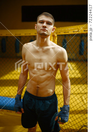 Male MMA fighter standing in a cage 72224417