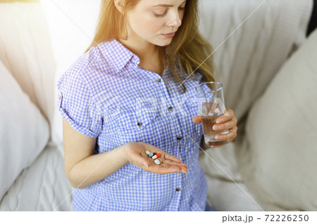 Close-up woman holding pills time to take medications, cure for headache. Medicine concept during self isolation and Coronavirus pandemic Close-up woman holding pills time to take medications, cure for headache. Medicine concept during self isolation and Coronavirus pandemic 72226250