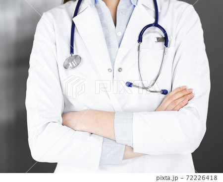 Unknown young woman doctor is standing with arms crossed in clinic. Medicine concept during Coronavirus pandemic Unknown young woman doctor is standing with arms crossed in clinic. Medicine concept during Coronavirus pandemic 72226418