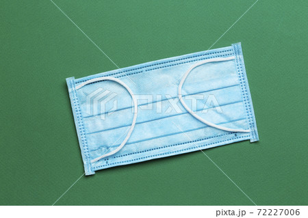 Surgical mask with rubber ear straps on a green background.  72227006