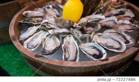 Fresh oysters with lemon in wooden barrel 72227886