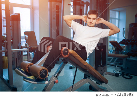 young athletic male or bodybuilder has abdominal workout or pump press in gym young athletic male or bodybuilder has abdominal workout or pump press in gym 72228998