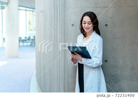 病院で白衣を着た笑顔のクリップボードを持つ女性医師 72231400