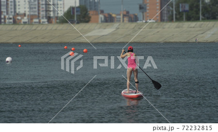 Athlete on stand up paddleboard sup holding paddle board up paddleboarding race. SUP surfboard. Athlete on stand up paddleboard sup holding paddle board up paddleboarding race. SUP surfboard. 72232815
