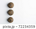 Diet vegetarian energy balls with nuts, dried fruit, oats, cocoa, peanut butter and honey, topped with chia seeds. White background. 72234359