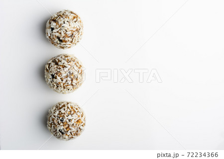 Diet vegetarian energy balls with nuts, dried fruit, chia, oats, cocoa, peanut butter and honey in coconut flakes. White background. Diet vegetarian energy balls with nuts, dried fruit, chia, oats, cocoa, peanut butter and honey in coconut flakes. White background. 72234366