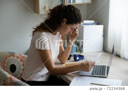 Unhappy stressed woman reading bad news in letter, holding paper 72234368