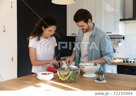Happy pleasant family cooking together, cutting vegetables in kitchen 72235004
