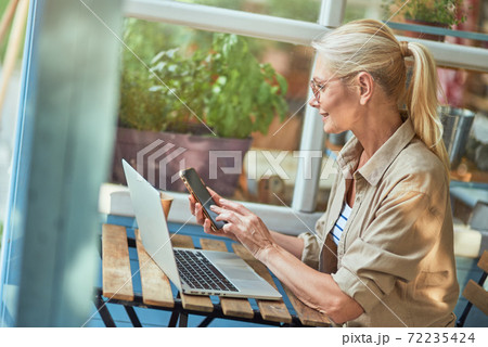 Middle aged caucasian woman dialing number on phone 72235424