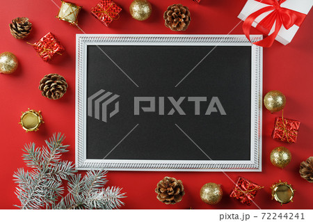 Photo frame with free black space around Christmas decorations and gifts on a red background 72244241