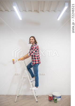 Young man in checkered shirt painting the wall 72246521