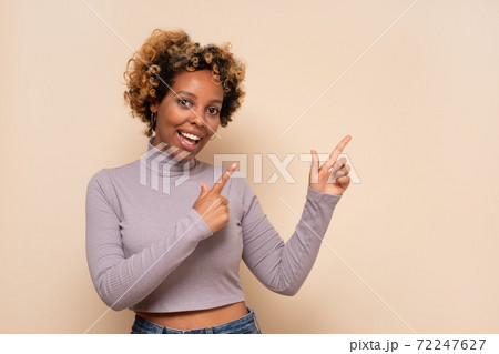 Attractive cheerful african woman with curly hair points aside, shows direction on free space Attractive cheerful african woman with curly hair points aside, shows direction on free space 72247627