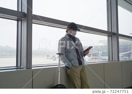 young asian man reading e-book using a e-reader while waiting for boarding in terminal building 72247751