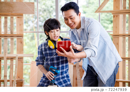 Asian father and son looking at digital tablet in carpentry workshop at home. Asian father and son looking at digital tablet in carpentry workshop at home. 72247939