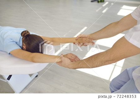 Hands of man chiropractor pulling lyong woman patients hands to fix her back and shoulder joint Hands of man chiropractor pulling lyong woman patients hands to fix her back and shoulder joint 72248353