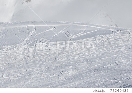 Snowy slope with traces of skis and snowboards 72249485