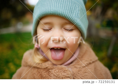 portrait of a little cute girl with sticking out tongue 72250131