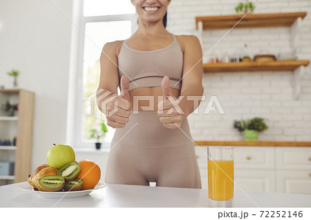 Cropped image of fitness woman in sports uniform showing thumbs up near fruits and fresh juice. 72252146