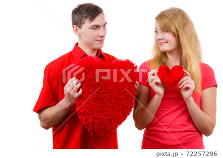 Couple holds red heart shaped pillows love symbol 72257296