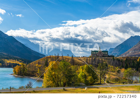 Middle Waterton Lake lakeshore in autumn foliage season sunny day morning. Blue sky, white clouds over mountains in the background. Landmarks in Waterton Lakes National Park, Alberta, Canada. Middle Waterton Lake lakeshore in autumn foliage season sunny day morning. Blue sky, white clouds over mountains in the background. Landmarks in Waterton Lakes National Park, Alberta, Canada. 72257340