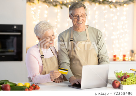 Elderly Couple Shopping Using Laptop And Credit Card In Kitchen Elderly Couple Shopping Using Laptop And Credit Card In Kitchen 72258496