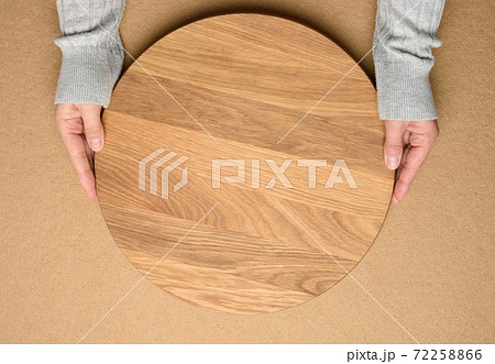 woman holding empty round wooden pizza board in hand woman holding empty round wooden pizza board in hand 72258866