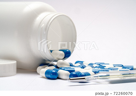 Medications capsules in a bottle and thermometer on light grey background Medications capsules in a bottle and thermometer on light grey background 72260070