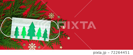 Christmas trees cut out of paper with medical disposable face mask and green fir branches on a red background. 72264451