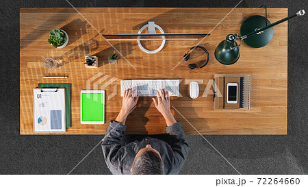 Top view of businessman working on computer at desk with keyable screen in home office. 72264660