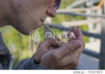 Close-up of young man smoking marijuana joint outdoors Close-up of young man smoking marijuana joint outdoors 72267820