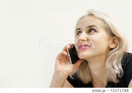 A young girl with blond hair communicates on the phone. 72271788