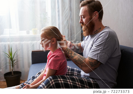 Father is combing his blonde daughter's hair 72273373